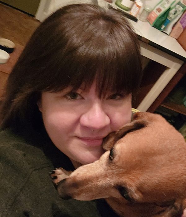 Abi cuddling a small brown dog