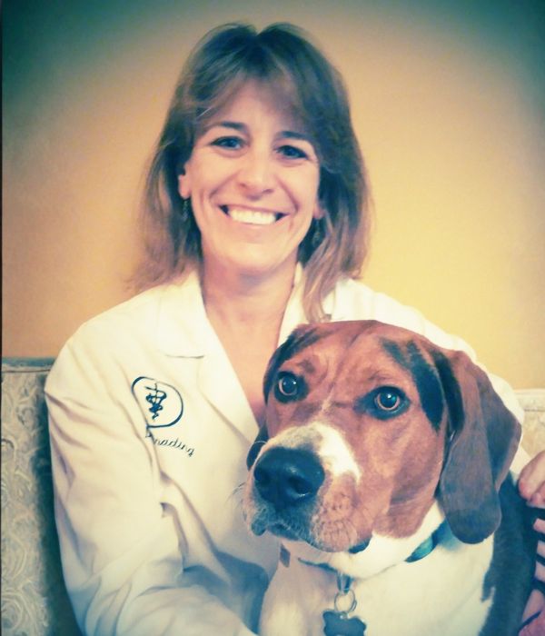 Dr. Schrading smiling with a brown and white dog