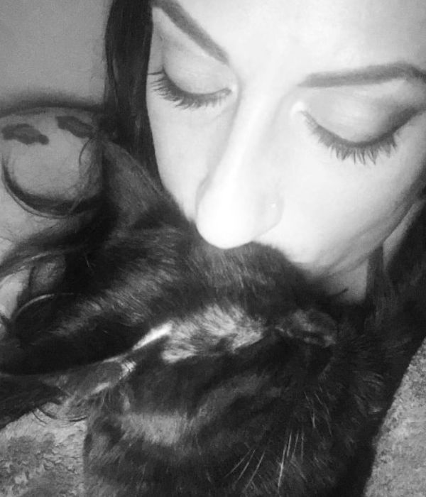 Shara kissing a black cat in a black and white photo
